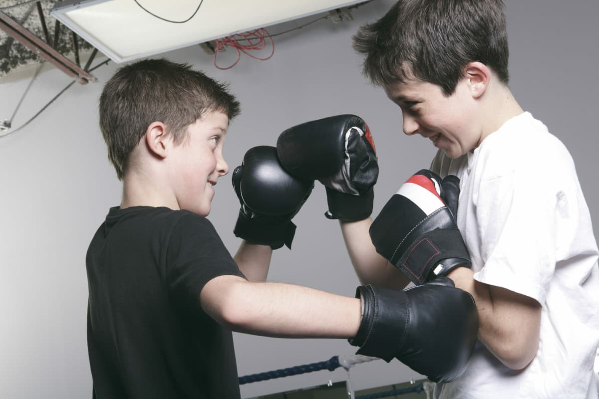 Twee jongens met bokshandschoenen oefenen samen een stoot