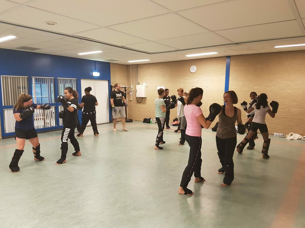 Kinderen oefenen in tweetallen stoten en trappen tijdens een kickboksles